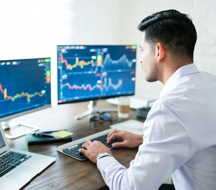 Trader analysant plusieurs écrans de graphiques en temps réel